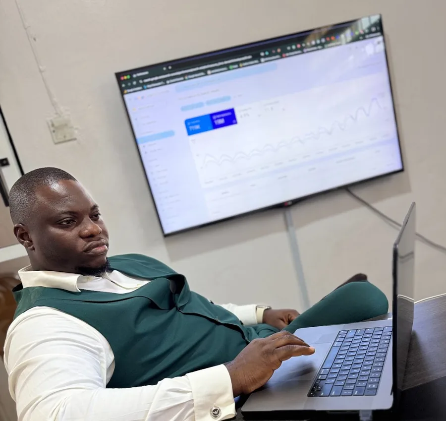 Fredrick Eghosa working at his laptop in front of an analytics dashboard